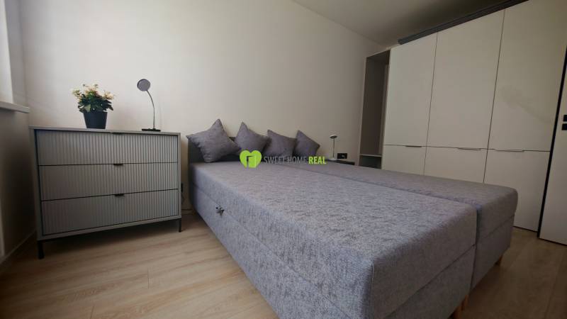 Schlafzimmer mit Bett, Schrank und Kommode in einer Einzimmerwohnung.