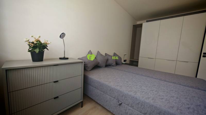 Schlafzimmer mit Doppelbett, Schrank, Kommode und Dekoration in einer Einzimmerwohnung.