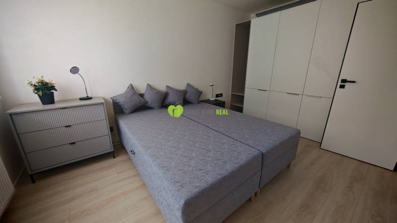Schlafzimmer in einer Einzimmerwohnung mit zwei Betten, einer Kommode und einem großen Schrank.
