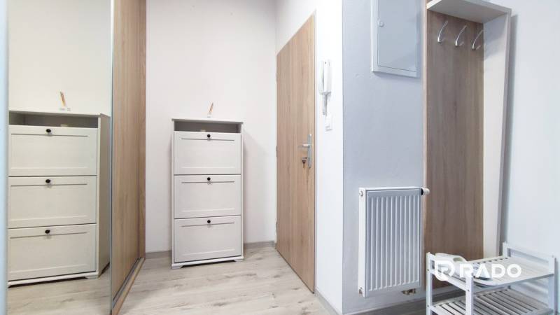 Flur mit weißen Möbeln und Kleiderhaken in einer 2-Zimmer-Wohnung, helle Holzböden.
