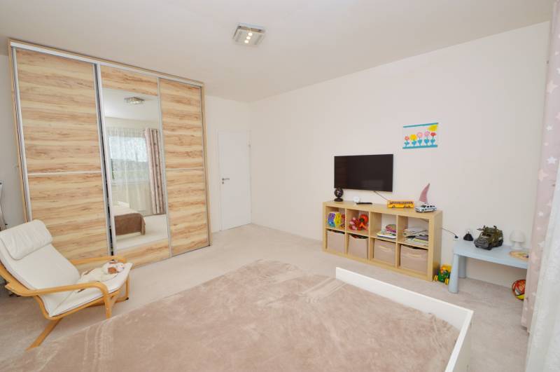 Kinderzimmer in einem Einfamilienhaus mit Einbauschrank, Fernseher und Regalen mit Spielzeug.