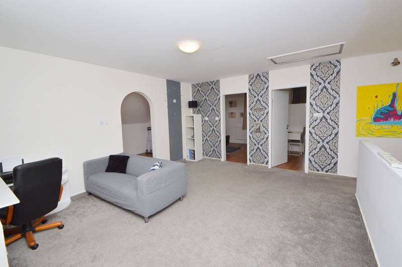 Innenraum eines Einfamilienhauses mit Sessel, Sofa und auffälligen Tapeten an der Wand.