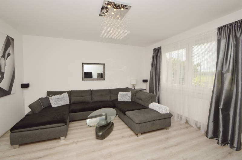 Wohnzimmer in einem Einfamilienhaus mit dunklem Sofa und Glastisch.