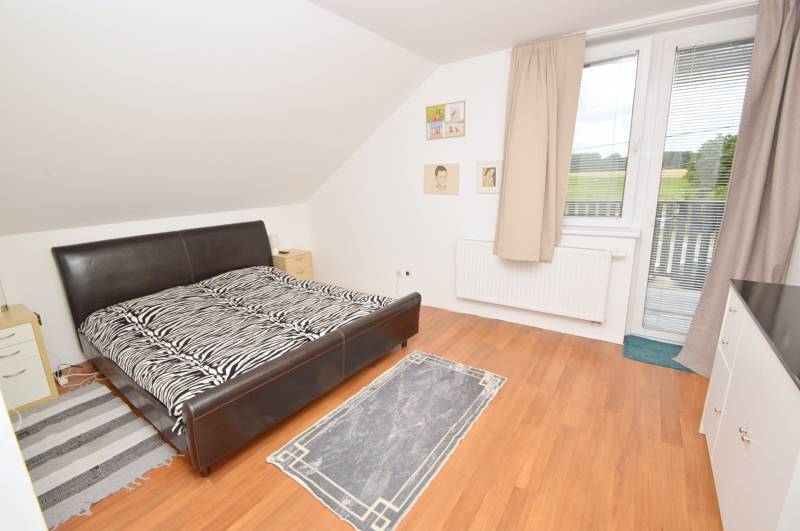 Schlafzimmer im Einfamilienhaus mit Ehebett, Teppichen und großem Fenster.