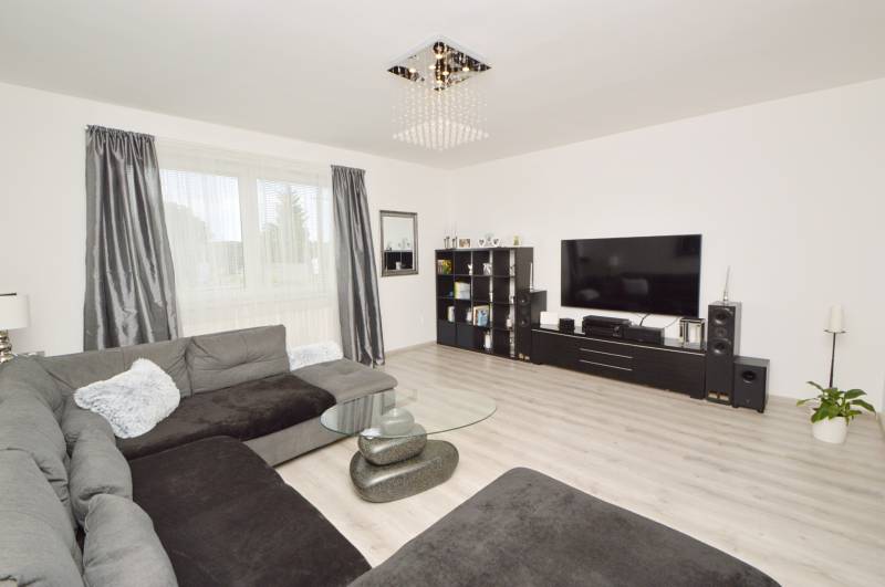 Wohnzimmer mit großer Couch, Glastisch und Fernseher in einem Einfamilienhaus.
