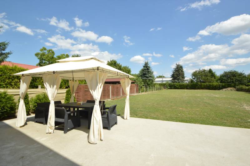 Eine Terrasse mit Pavillon im Garten eines Einfamilienhauses in Rajka, umgeben von Grün und Rasen.