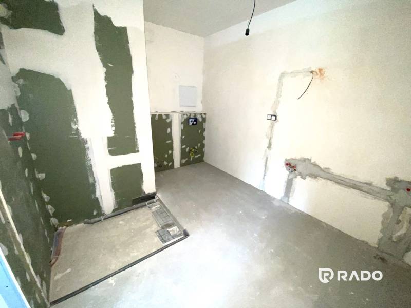 Innenraum einer unvollendeten 2-Zimmer-Wohnung mit vorbereiteten Leitungen an den Wänden.