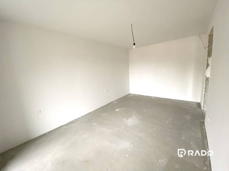 Ein leerer Raum in einer Zweizimmerwohnung mit weißen Wänden und Betonboden.