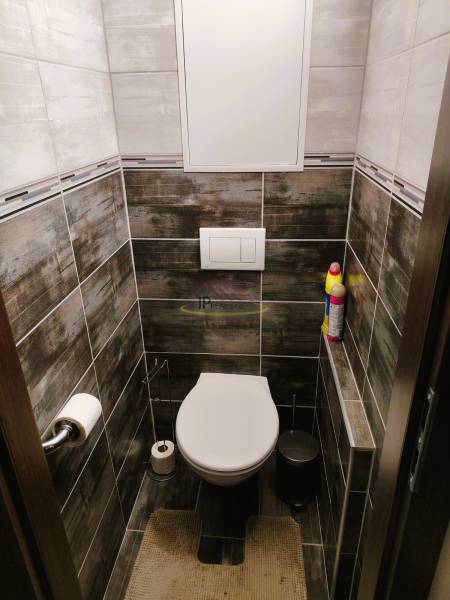 Badezimmer mit hängendem WC, Fliesen in einer 2-Zimmer-Wohnung mit dunklen Fliesen.