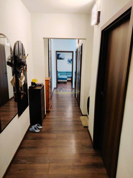 Flur einer 2-Zimmer-Wohnung mit Holzboden und Eingang zum Wohnzimmer.
