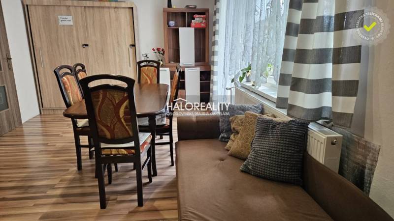 Esszimmer in einem Einfamilienhaus mit Holztisch, Stühlen und Sofa, helle Vorhänge.