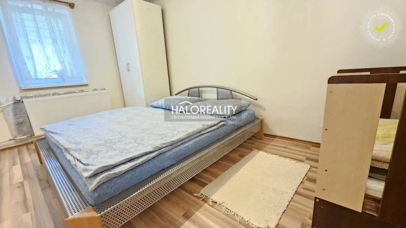Ein Schlafzimmer in einem Einfamilienhaus, einfach eingerichtet mit einem Bett, einem Schrank und einem Holzboden.