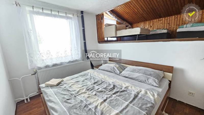 Ein Schlafzimmer in einem Einfamilienhaus mit einem einfachen Bett und einem Dachbodenbereich mit einem weiteren Bett.