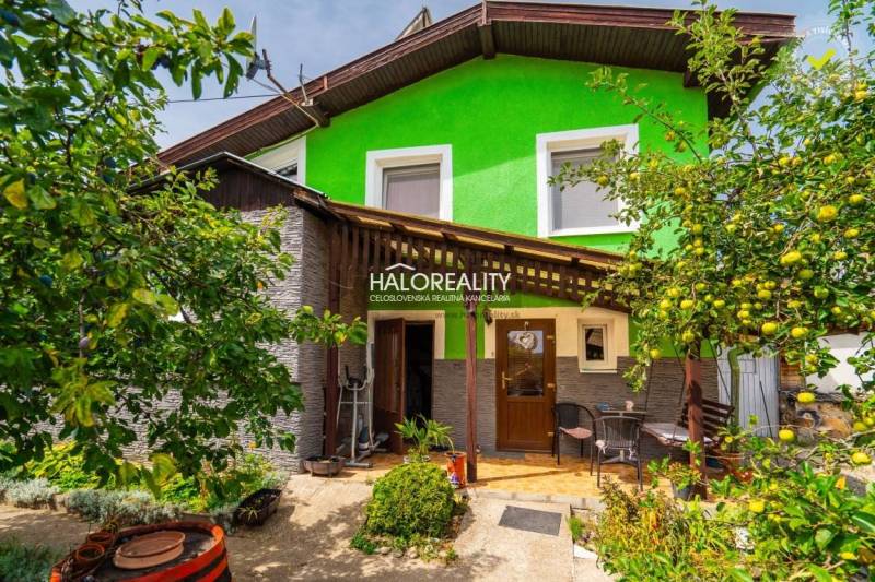 Ein Einfamilienhaus in Banská Štiavnica mit einer Holzveranda, umgeben von Grün und Obstbäumen.