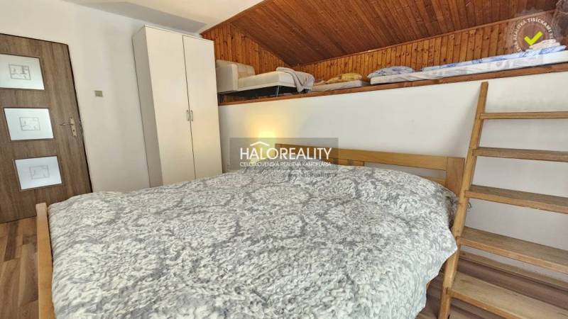 Schlafzimmer in einem Einfamilienhaus mit Holzverkleidung und einer Leiter zum Obergeschoss.