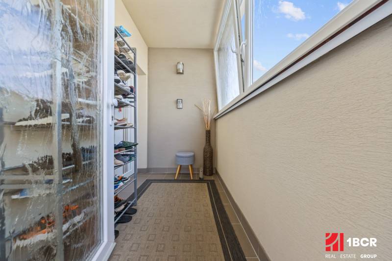 Balkon in einer 4-Zimmer-Wohnung mit Schuhschrank, Teppich, Verglasung, offenes Fenster.