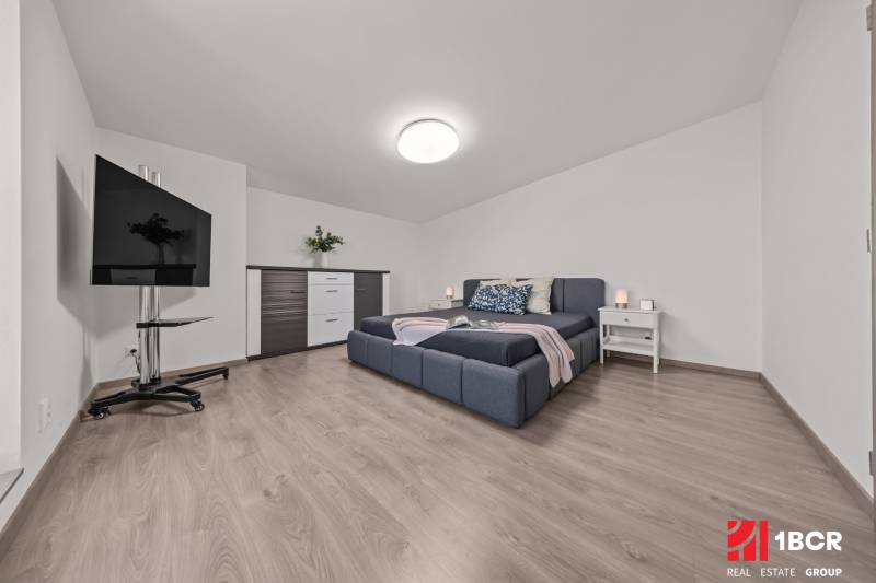 Helles Schlafzimmer mit großem Bett, Fernseher und Kommode in einer 4-Zimmer-Wohnung.