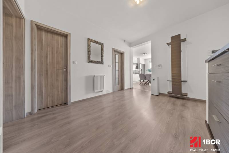 Flur einer 4-Zimmer-Wohnung mit Holztüren, Spiegel und Blick in die Küche.