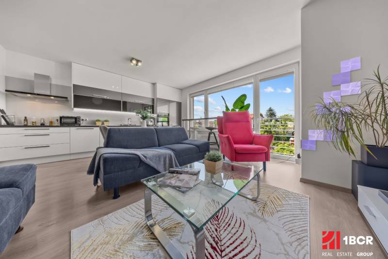 Wohnzimmer mit Sofa und Sessel in einer 4-Zimmer-Wohnung. Große Fenster mit Aussicht.