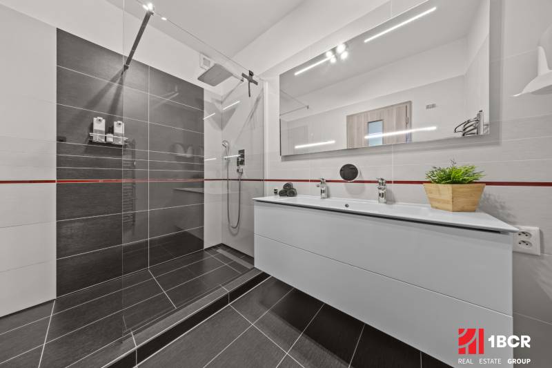 Badezimmer in einer 4-Zimmer-Wohnung mit Duschkabine und Doppelwaschbecken.