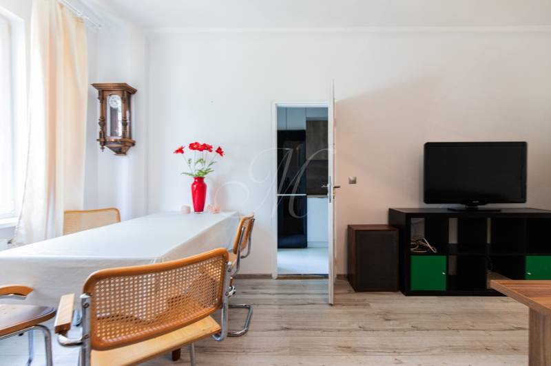 Esszimmer in einer 4-Zimmer-Wohnung mit Holzstühlen, Fernseher und roter Vase.