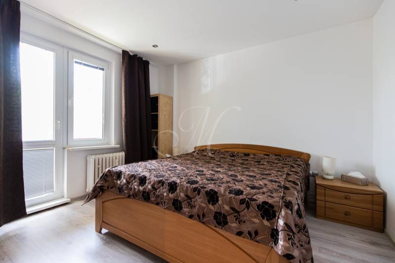 Schlafzimmer mit einem Holzbett und dunklen Vorhängen in einer 4-Zimmer-Wohnung.