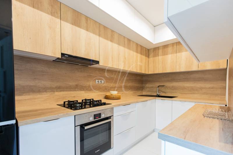 Küche einer 4-Zimmer-Wohnung mit Holzschränken und eingebauten Geräten.