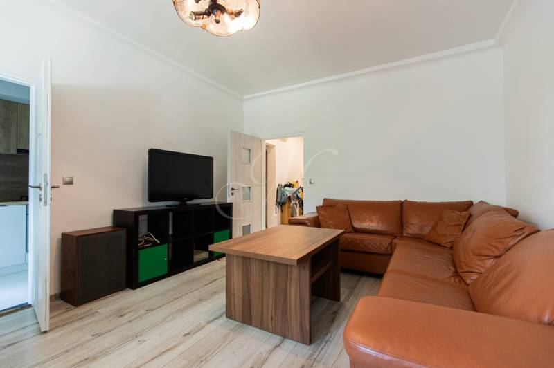 Wohnzimmer in einer 4-Zimmer-Wohnung mit Ledersofa und Fernseher auf einem Schrank.