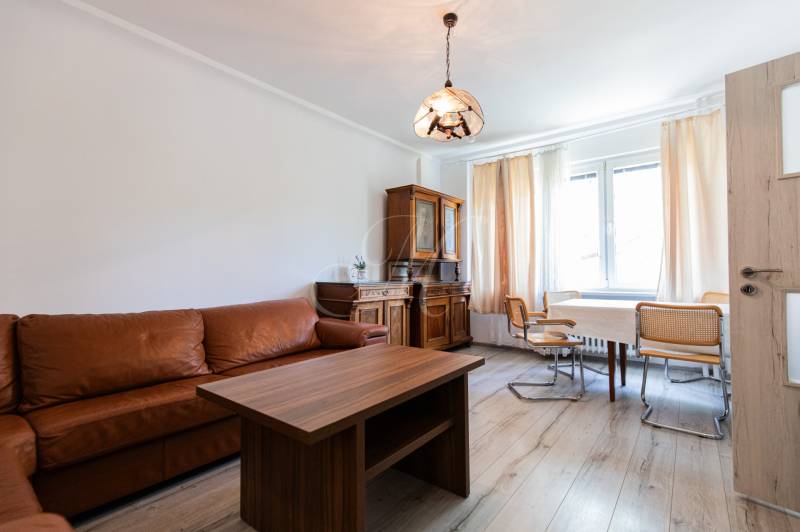 Wohnzimmer mit Sofa, Holztisch und Stühlen in einer 4-Zimmer-Wohnung.