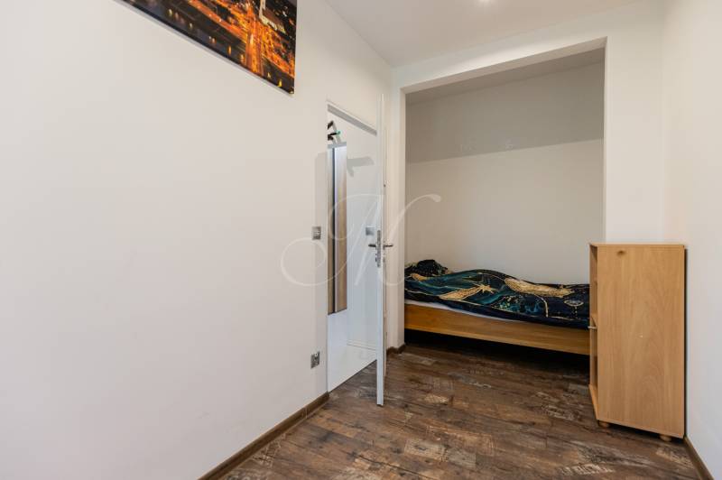 Ein kleines Schlafzimmer mit einem Bett und Holzboden in einer Vierzimmerwohnung.