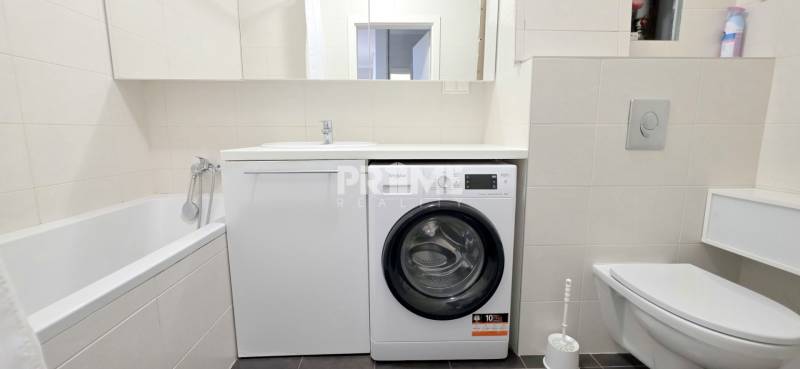 Badezimmer in einer 2-Zimmer-Wohnung mit Badewanne, Waschmaschine und Toilette.
