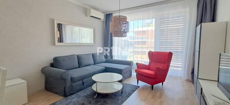 Ein stilvolles Wohnzimmer mit einem bequemen Sofa und einem roten Sessel in einer Zweizimmerwohnung.