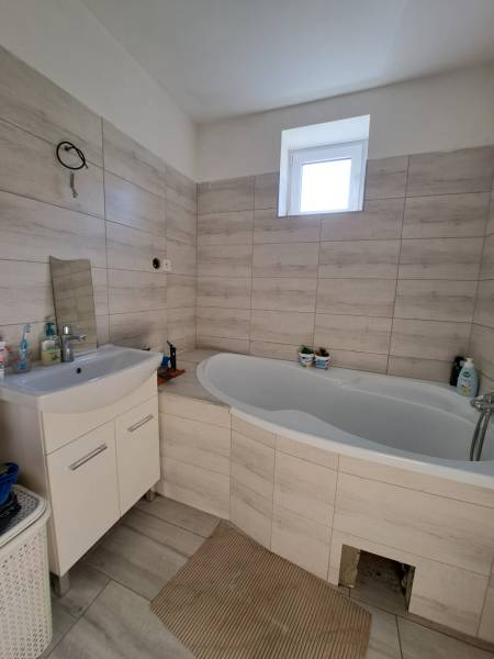 Badezimmer in einem Einfamilienhaus mit Badewanne und Waschbecken in hellen Farbtönen.