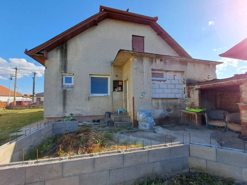 Ein Einfamilienhaus in Kmeťovo mit älterer Fassade und einem Garten im Bau.