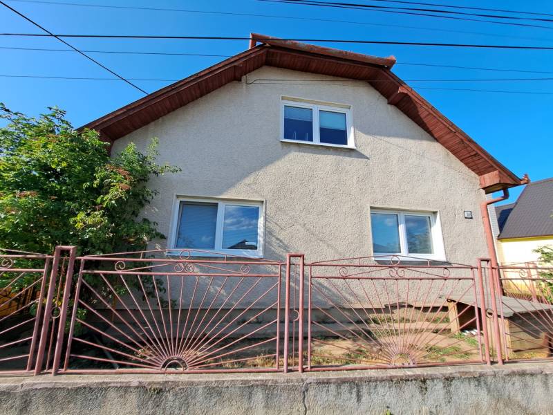Ein Einfamilienhaus in Kmeťovo mit weißer Fassade und einem Metallzaun.