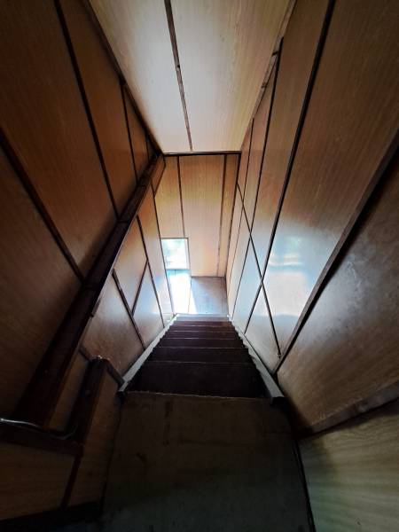 Eine Treppe mit Holzwänden, die zu einem schmalen Fenster in einem Einfamilienhaus führt.