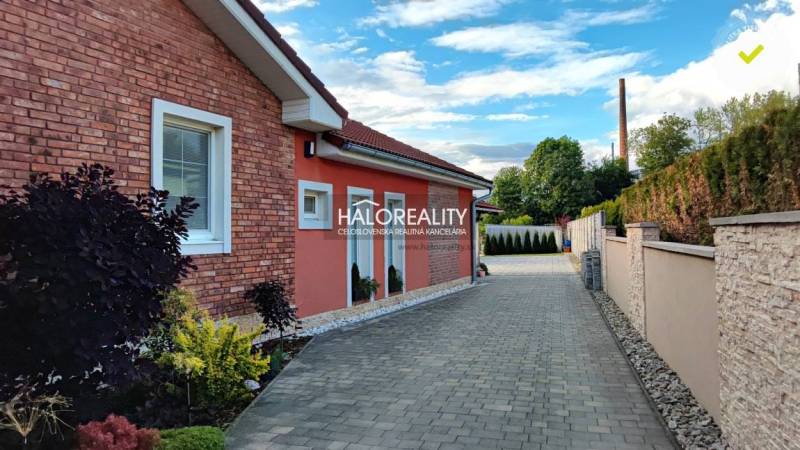 Ein Einfamilienhaus in Kalinovo mit einer Ziegelfassade, einem gepflasterten Gehweg und einem gepflegten Garten.