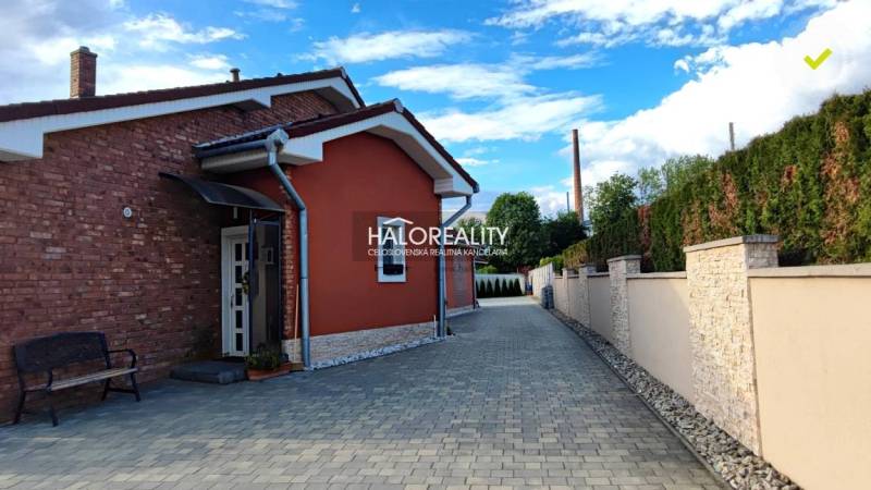 Ein Einfamilienhaus in Kalinovo mit Pflastersteinen und einer Ziegelfassade, umgeben von einer Mauer.