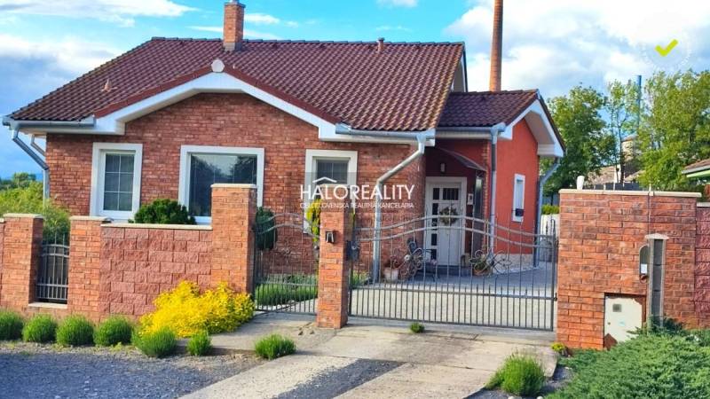 Ein Einfamilienhaus in Kalinovo mit einer Ziegelfassade, einem dekorativen Zaun und Gartenelementen.