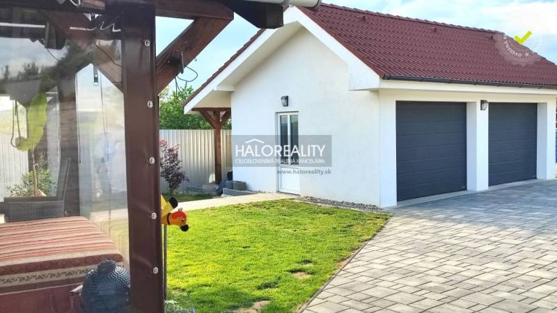 Außenbereich eines Einfamilienhauses in Kalinovo mit Rasen, Terrasse und Doppelgarage.