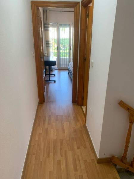 Der Flur des Einfamilienhauses führt in ein Zimmer mit einem Bett und einem Schreibtisch.
