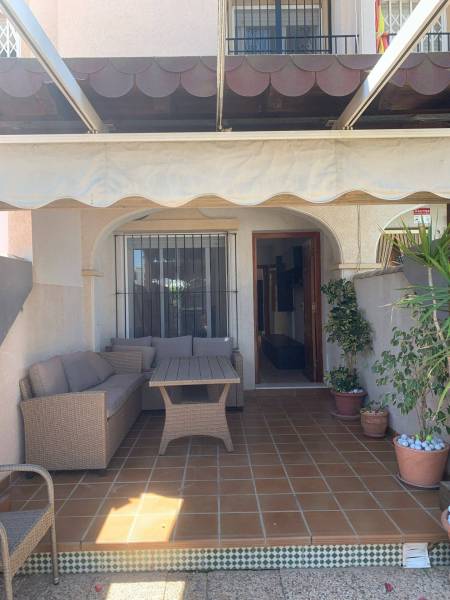 Ein Einfamilienhaus in Santiago de la Ribera mit Terrasse, Holzmöbeln und Blumentöpfen.