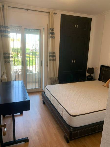 Schlafzimmer im Einfamilienhaus mit Bett, Schreibtisch und Zugang zum Balkon.