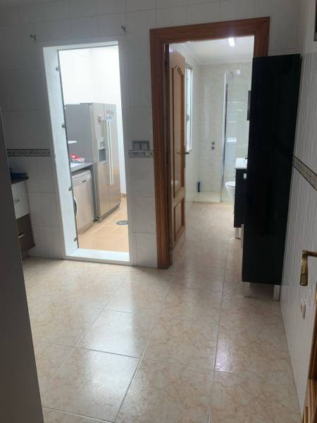 Der Flur mit Zugang zum Badezimmer und zur Küche im Einfamilienhaus, helle Fliesen.