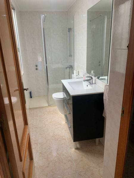 Badezimmer in einem Einfamilienhaus mit Waschbecken, Duschkabine und hellen Fliesen.