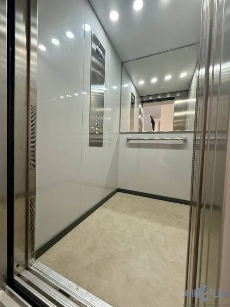 Ein Aufzug mit Metallwänden und Spiegel, geeignet für eine Zweizimmerwohnung.