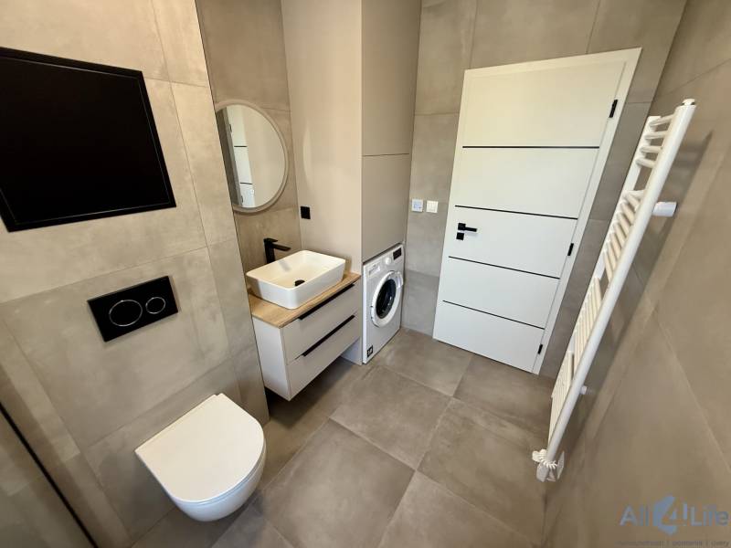 Badezimmer in einer 2-Zimmer-Wohnung mit Waschmaschine und moderner Sanitärausstattung.