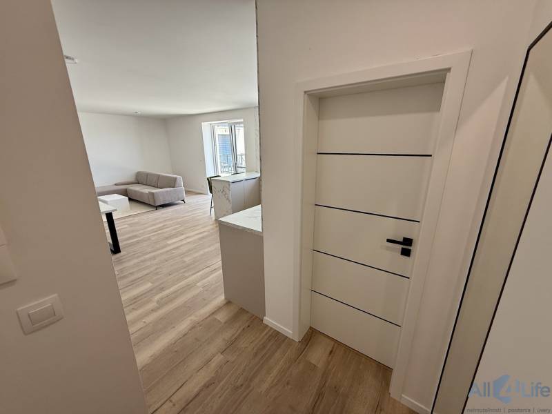 Eingangsbereich, der zum Wohnzimmer in einer 2-Zimmer-Wohnung mit Holzboden führt.