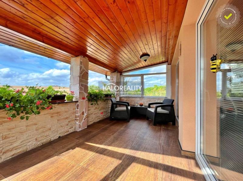 Eine verglaste Terrasse mit Holzdecke und Blumen in einem Einfamilienhaus.