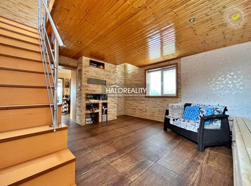 Innenraum eines Einfamilienhauses mit Holzdecke, Treppe und Sitzgarnitur.